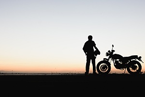 a man with his motorcycle admiring the sunrise
