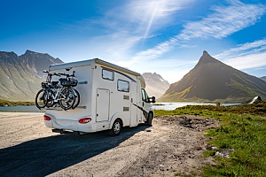 an rv parked in front of a lake with mountains in the background
