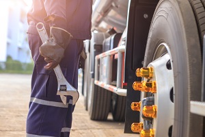 mechanic with large wrench in hand taking look at on the truck