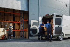 warehouse technicians unloading a cargo truck and pushing boxes into storage