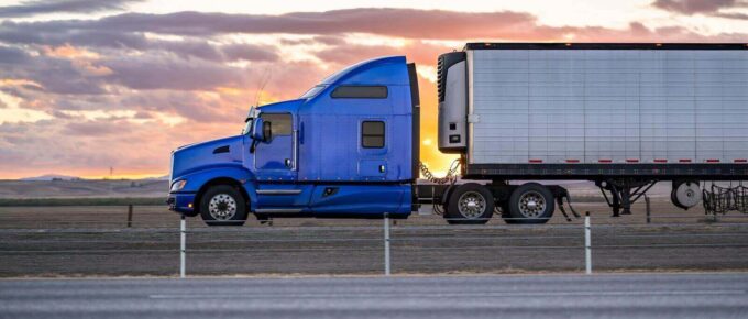 blue classic bonnet big rig semi truck with extended cab transporting cargo in refrigerated semi trailer