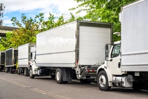 middle duty day cab rig semi trucks with refrigerated box trailers standing on the city street