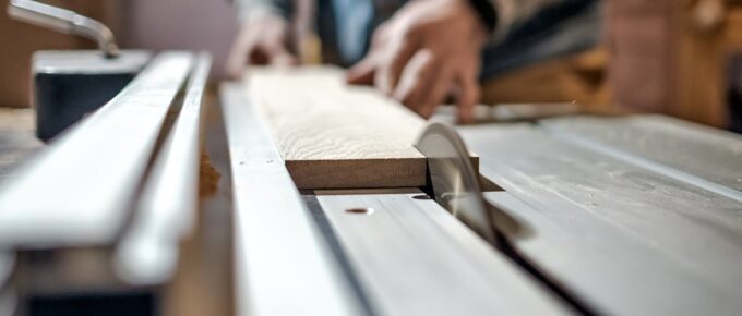 caucasian man making wooden parts for custom furniture on machine tool called thickness planer in carpentry