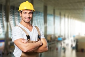 young builder in hardhat on blurred construction