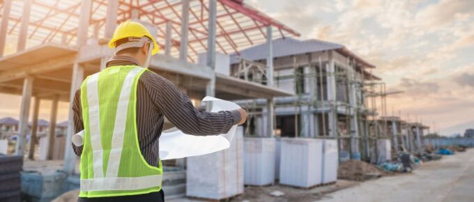 professional engineer architect worker with protective helmet and blueprints paper at house building construction site