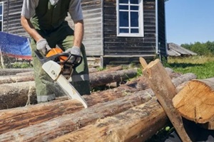 man cutting wood logs with a chainsaw