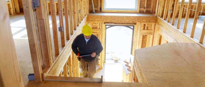 building inspector looking at new home, holding tablet with hard hat