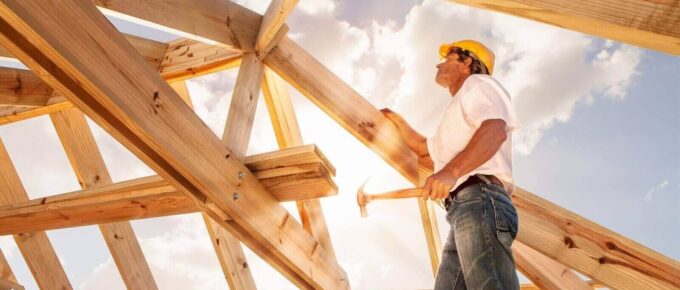 roofer builder working on roog structure of building on construction site