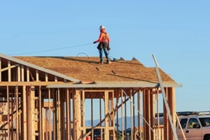 construction worker atop the structure of a home under construction in a new subdivision