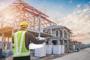 professional engineer architect worker with protective helmet and blueprints paper at house building construction site