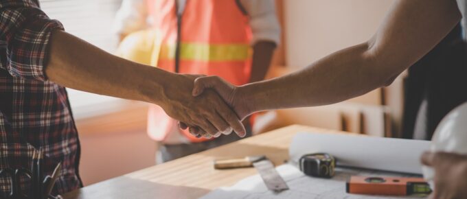 male architect shaking hands with client in construction site after confirm blueprint for renovate building