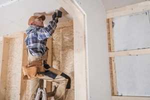 general construction contractor worker attaching drywall using drill driver