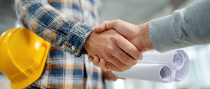 architecture and home renovation concept builder with blueprint shaking partner hand no logos no brands