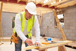 carpenter cutting house roof supports on building site