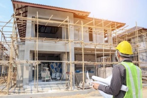 engineer architect worker with protective helmet and blueprints paper at house building construction site