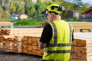 site worker inspects stacked lumber for house building and carpentry supply at outdoor work area